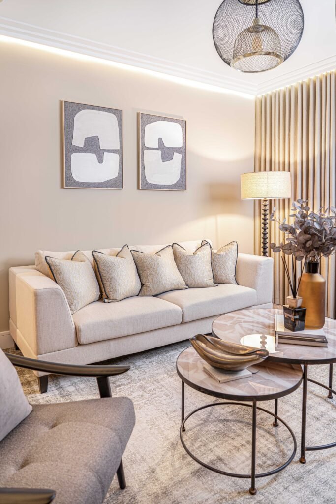 Modern living room with cream sofa, abstract wall art and warm accent lighting — The Steeples Part One by AK Interior, Cork