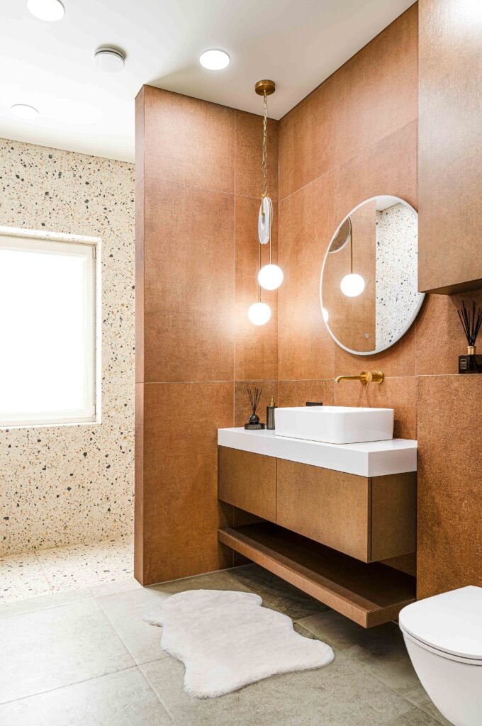 Warm modern bathroom with tan wall tiles, floating vanity and round mirror, AK Interior Design, Cork, Ireland.