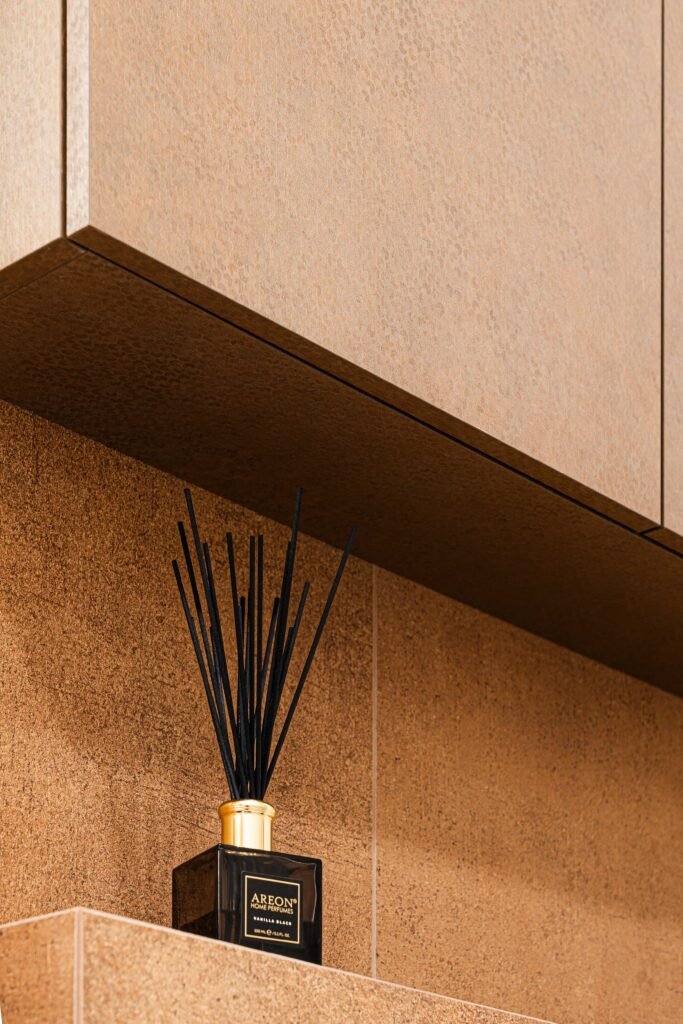 Upper bathroom cabinet and black reed diffuser on warm brown tiles, AK Interior Design, Cork, Ireland.