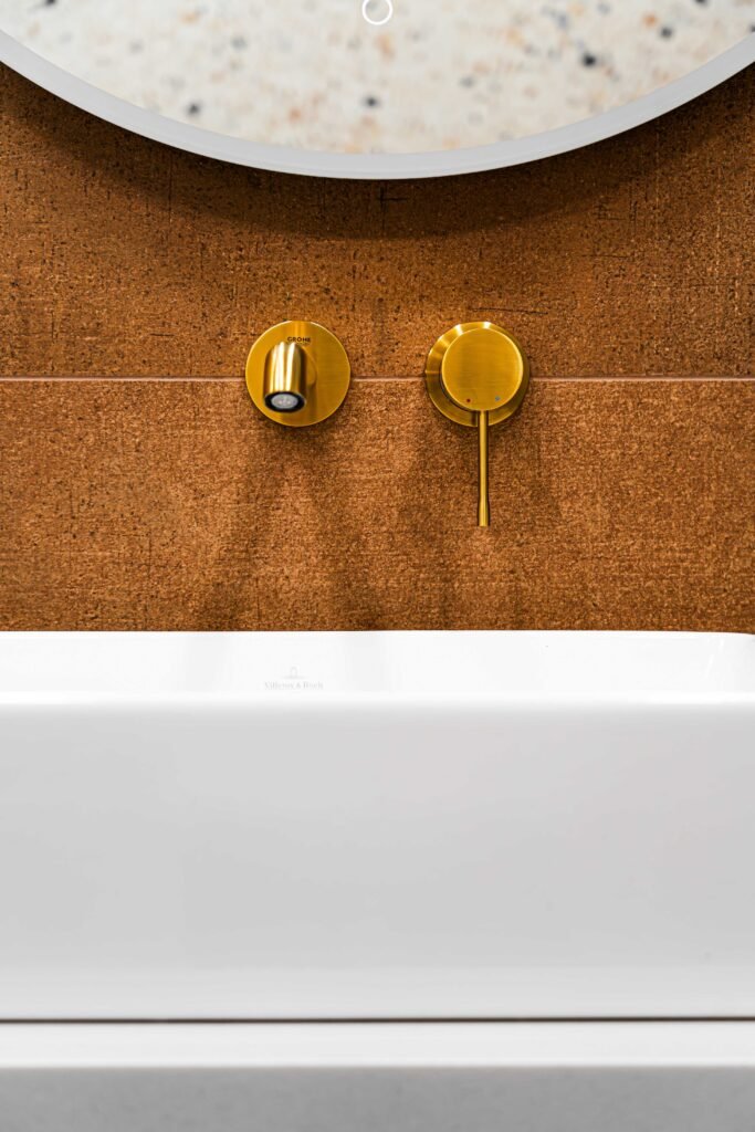 Brass wall-mounted tap set above rectangular basin and round mirror, AK Interior Design, Cork, Ireland.