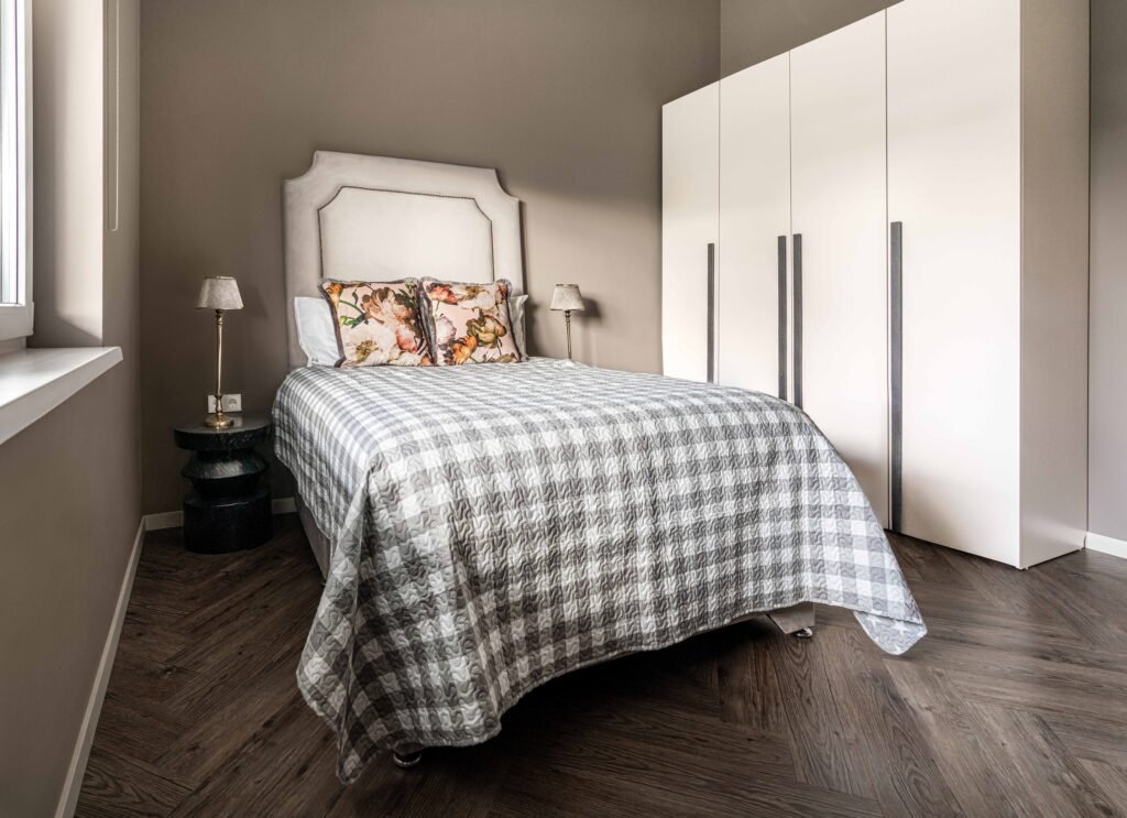 Guest bedroom with light bed frame, patterned bedding and minimalist décor – Monkstown Full House Design by AK Interior.