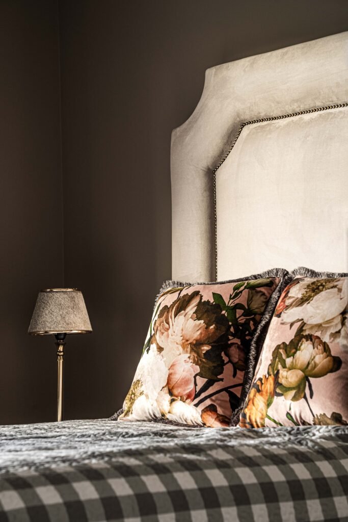 Close-up of a dark-toned bedroom with a soft headboard and floral decorative pillows – AK Interior, Monkstown Full House Design