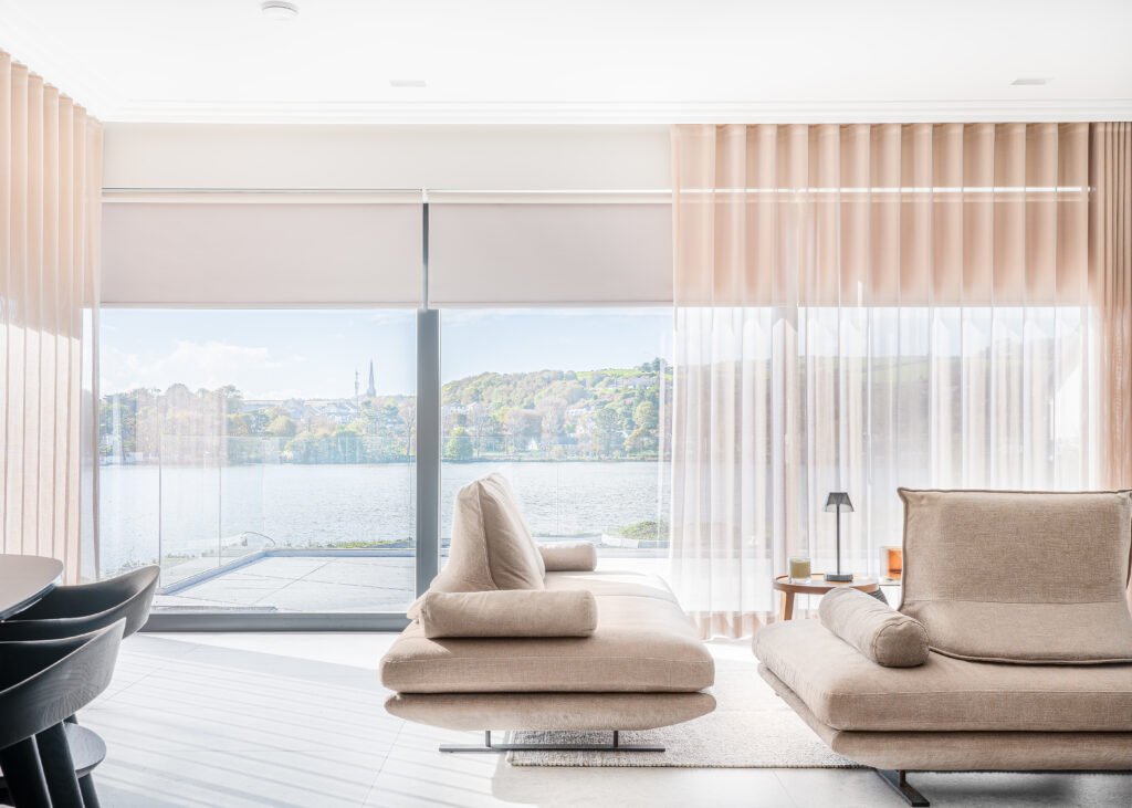 Bright living room with full-height sheer curtains and contemporary seating – Residential project “West Cork Waterfront”, designed by AK Interior, Cork, Ireland.
