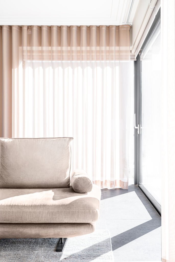 Cozy corner with beige armchair, black round side table and layered curtains – West Cork Waterfront, residential project by AK Interior, Cork, Ireland.