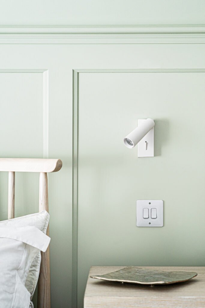 Panelled bedroom wall with minimal white bedside sconce – West Cork Waterfront, residential project by AK Interior, Cork, Ireland.