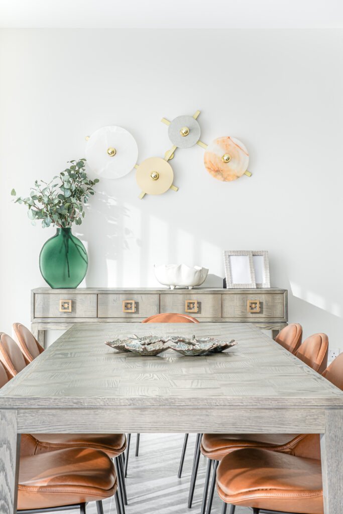 Light dining area with pale wood table, tan leather chairs and floral wall art. Rosscarbery Residence residential project, AK Interior.