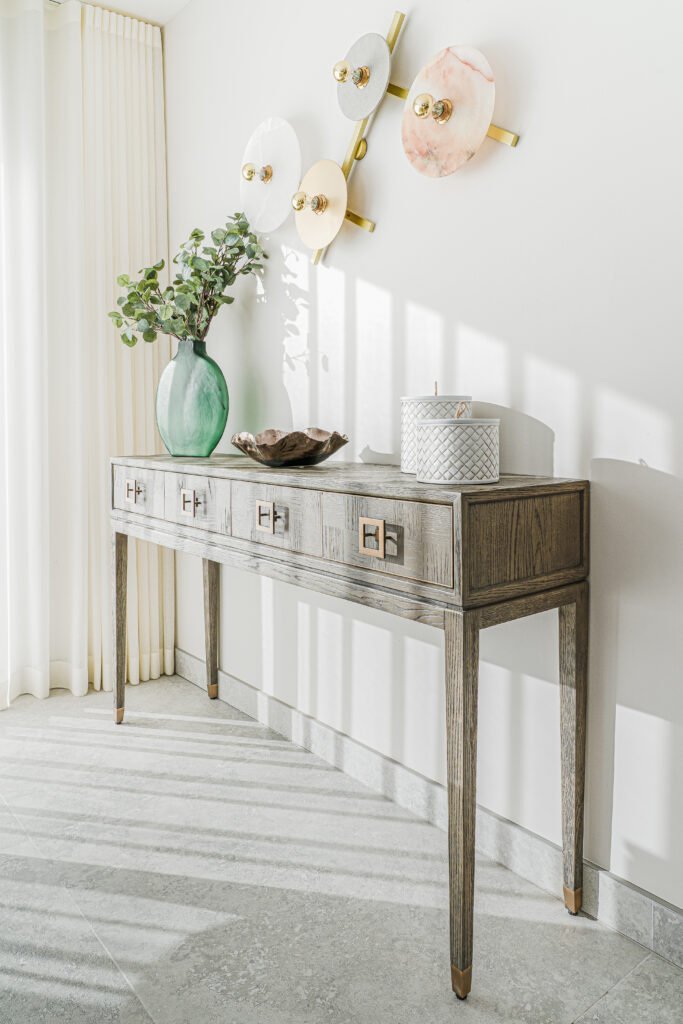 Console table styling with flowers and wall plates in bright hallway. Rosscarbery Residence residential project, AK Interior.