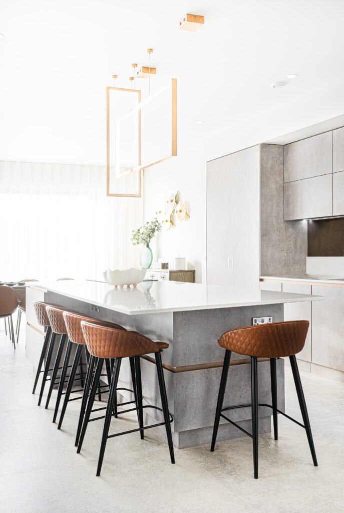 Minimal white and grey kitchen with large island and sculptural gold pendants. Rosscarbery Residence residential project, AK Interior.