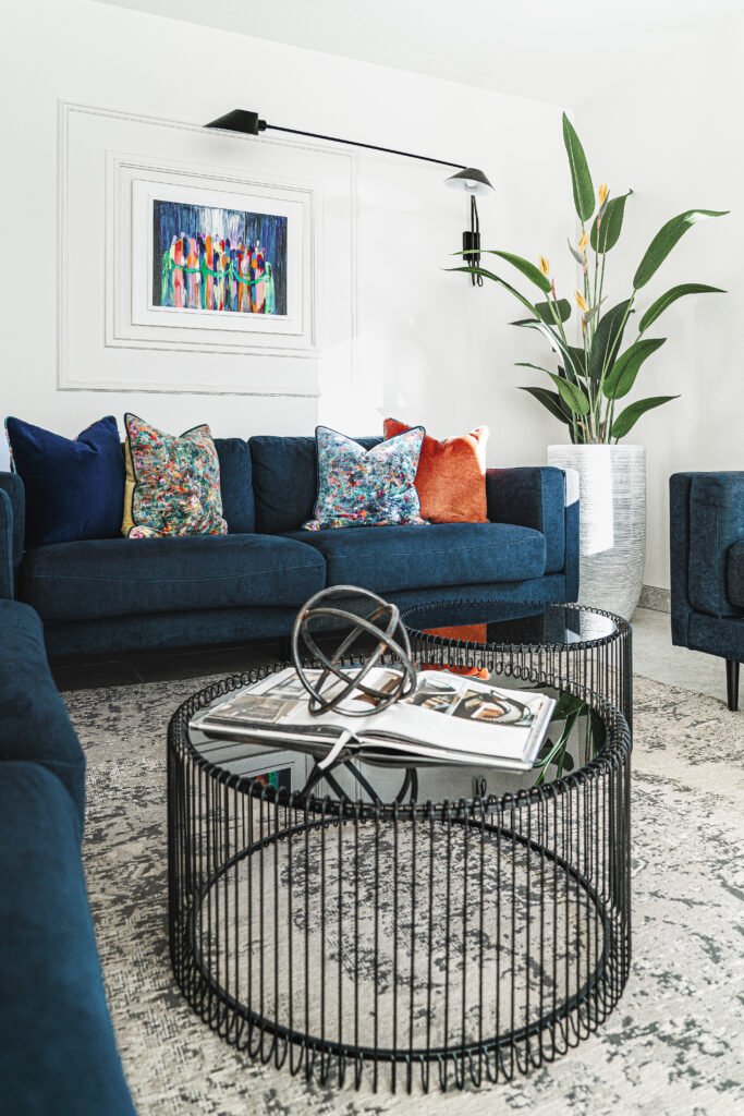 Contemporary living room with navy sofa, colourful cushions and large plant. Rosscarbery Residence residential project, AK Interior.