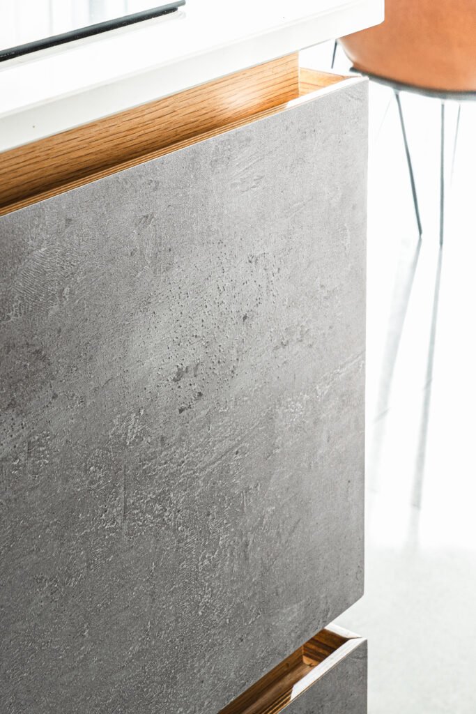 Detail of concrete-look cabinet side with warm timber trim. Rosscarbery Residence residential project, AK Interior.