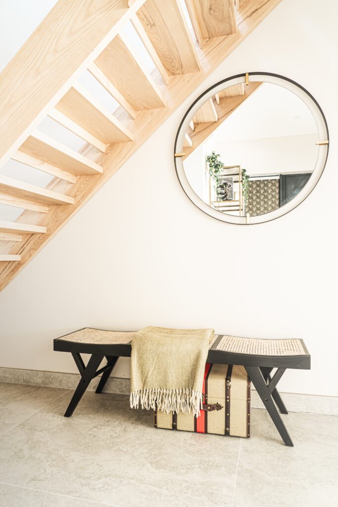 Hallway bench under timber staircase with throw and framed print. Rosscarbery Residence residential project, AK Interior.