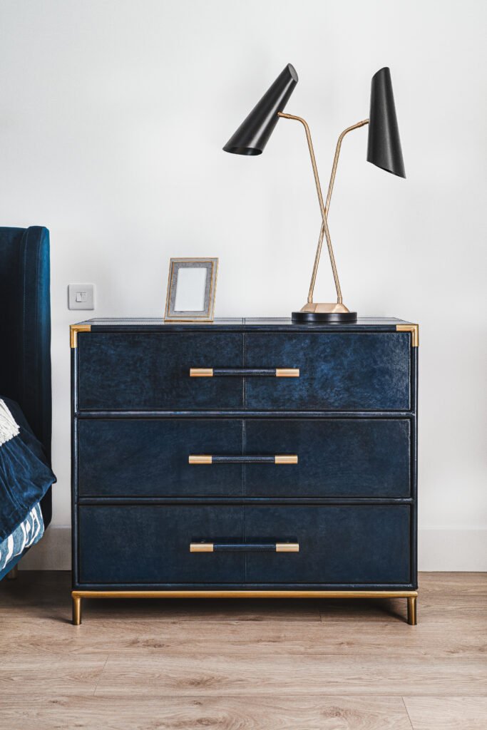 Navy chest of drawers with brass handles and double black table lamp. Rosscarbery Residence residential project, AK Interior.