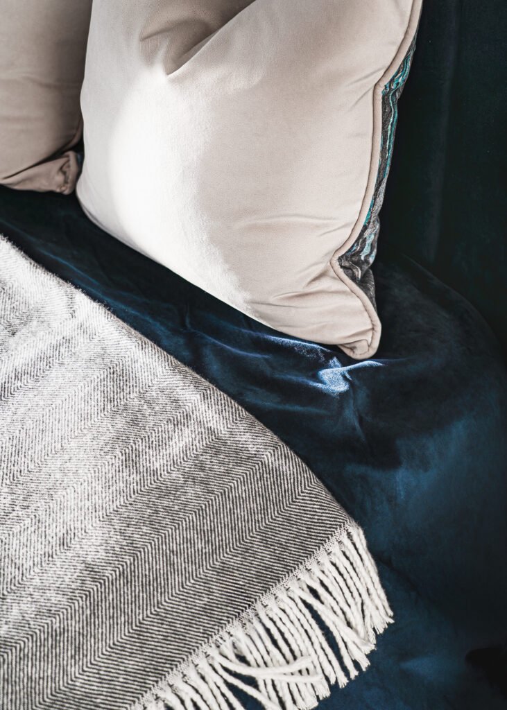 Close-up of layered neutral pillows and herringbone throw on velvet bed. Rosscarbery Residence residential project, AK Interior.