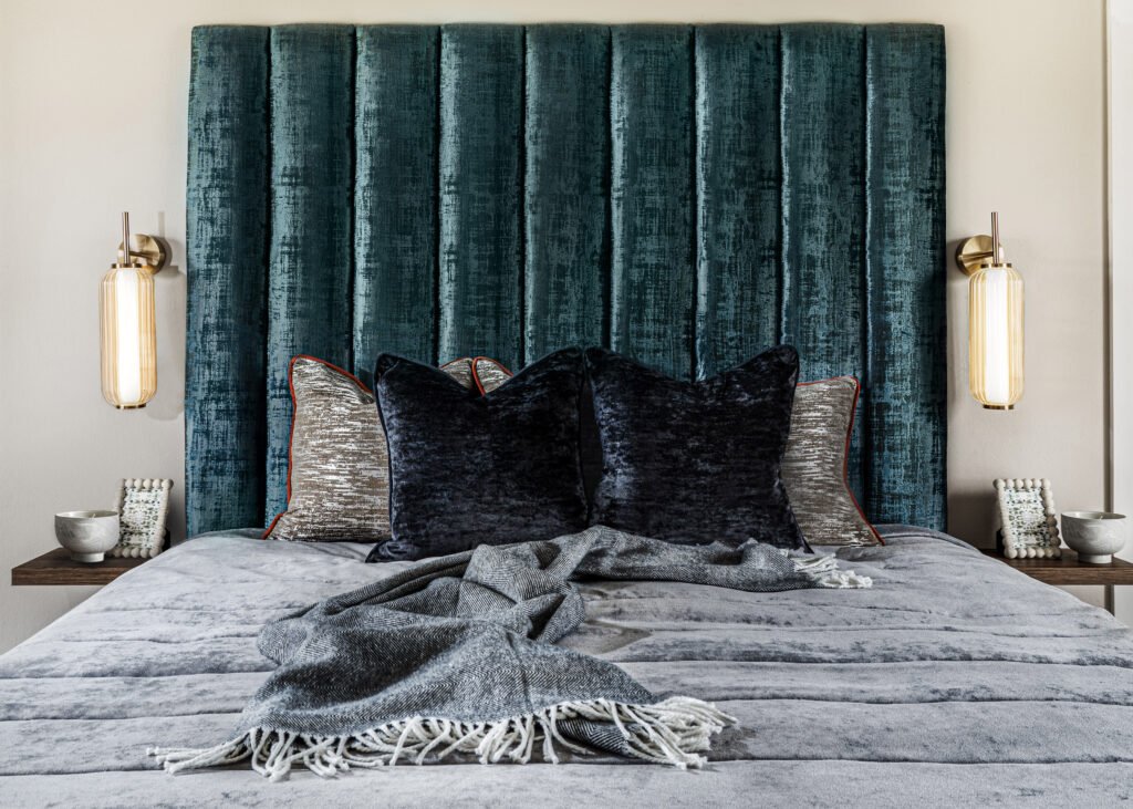 Front view of bed with teal headboard, textured cushions and cozy throw – Dingle project, designed by AK Interior, Cork, Ireland.
