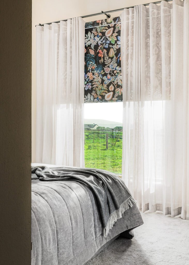 Bedroom window with sheer curtains and floral Roman blind – Dingle project, designed by AK Interior, Cork, Ireland.