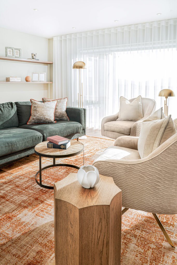Bright sitting room with green sofa, beige armchairs and orange patterned rug, AK Interior residential project.