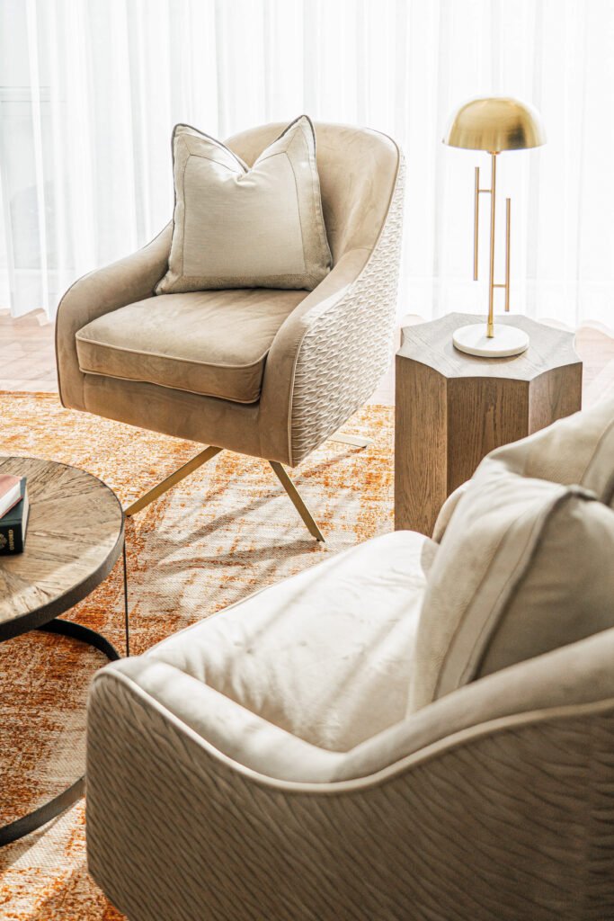 Cosy reading corner with woven armchair, round coffee table and brass lamp on octagonal side table, orange rug, Rosscarbery Reading Room, AK Interior, Cork.