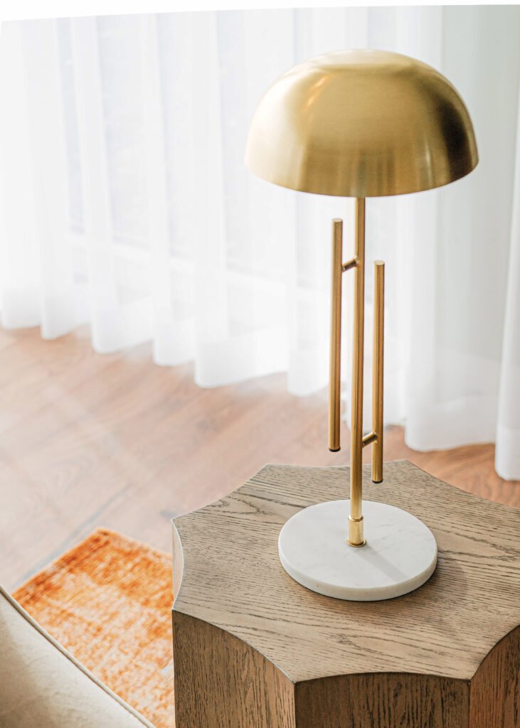 Close-up of brass and marble table lamp base on oak side table.