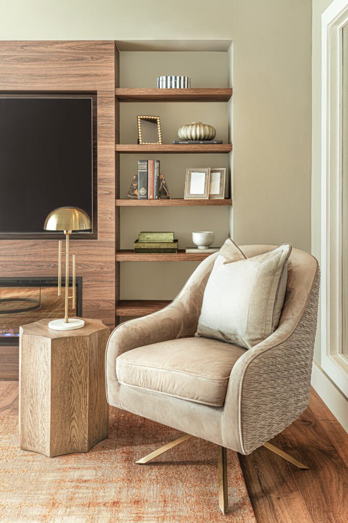 Cosy seating group with neutral armchair, orange rug and timber shelving, AK Interior residential project.