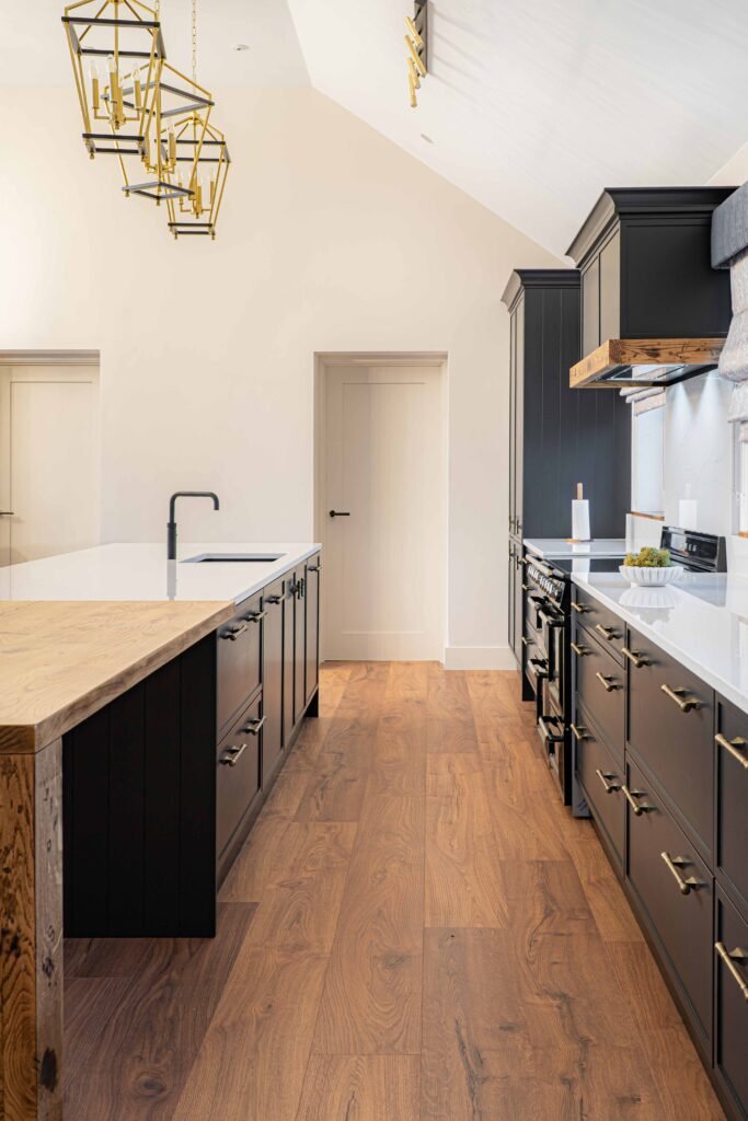 Wide view of kitchen walkway with black cabinetry and wood flooring – Dingle project, designed by AK Interior, Cork, Ireland.