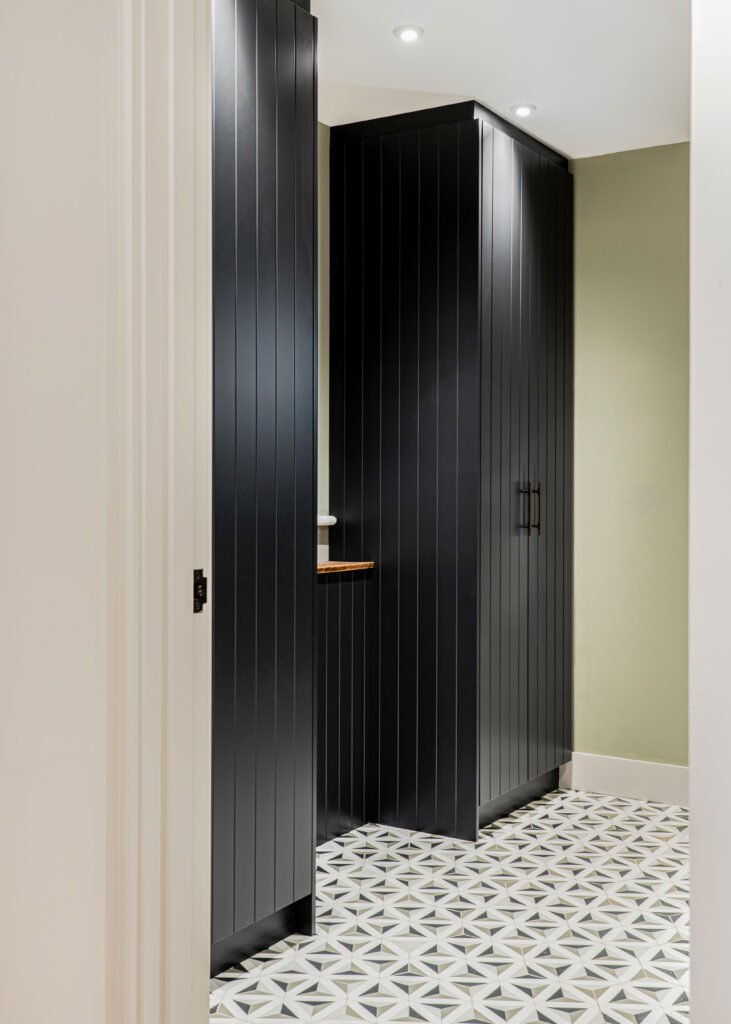 Black cabinet with styled décor pieces against pink tiled backdrop – Dingle project, designed by AK Interior, Cork, Ireland.