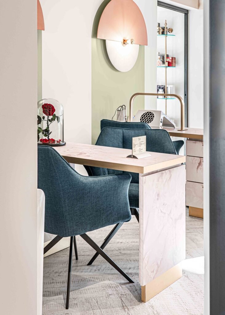 Modern manicure table with blue chairs and a soft pink wall light – Bon Me project, designed by AK Interior Cork.