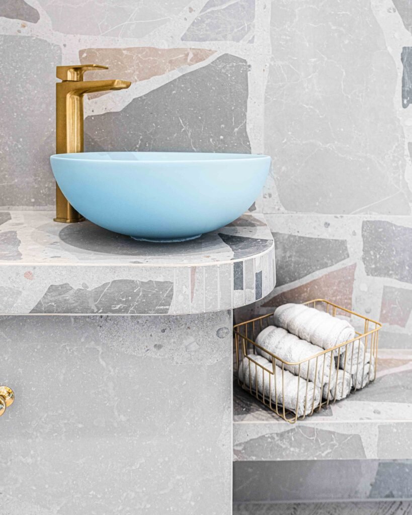 Blue basin with gold tap and neatly rolled towels in a wire basket – Bon Me project, designed by AK Interior Cork.