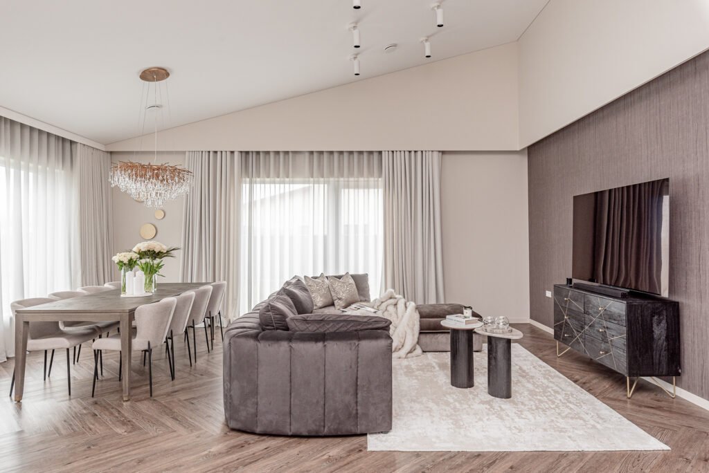 Bright living room with a soft grey sofa, dining area, and crystal chandelier. Project Monkstown Full House Design – AK Interior